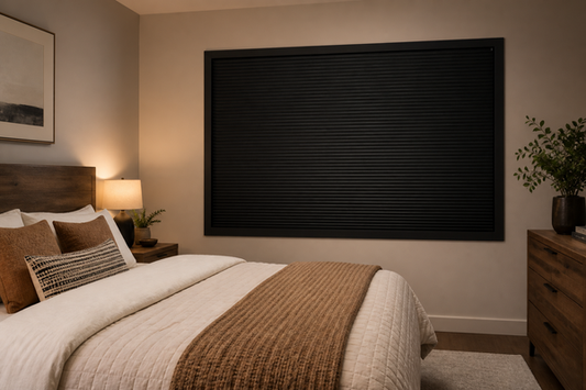Dawn bedroom with a fully closed black framed cellular blackout shade and no visible edge light